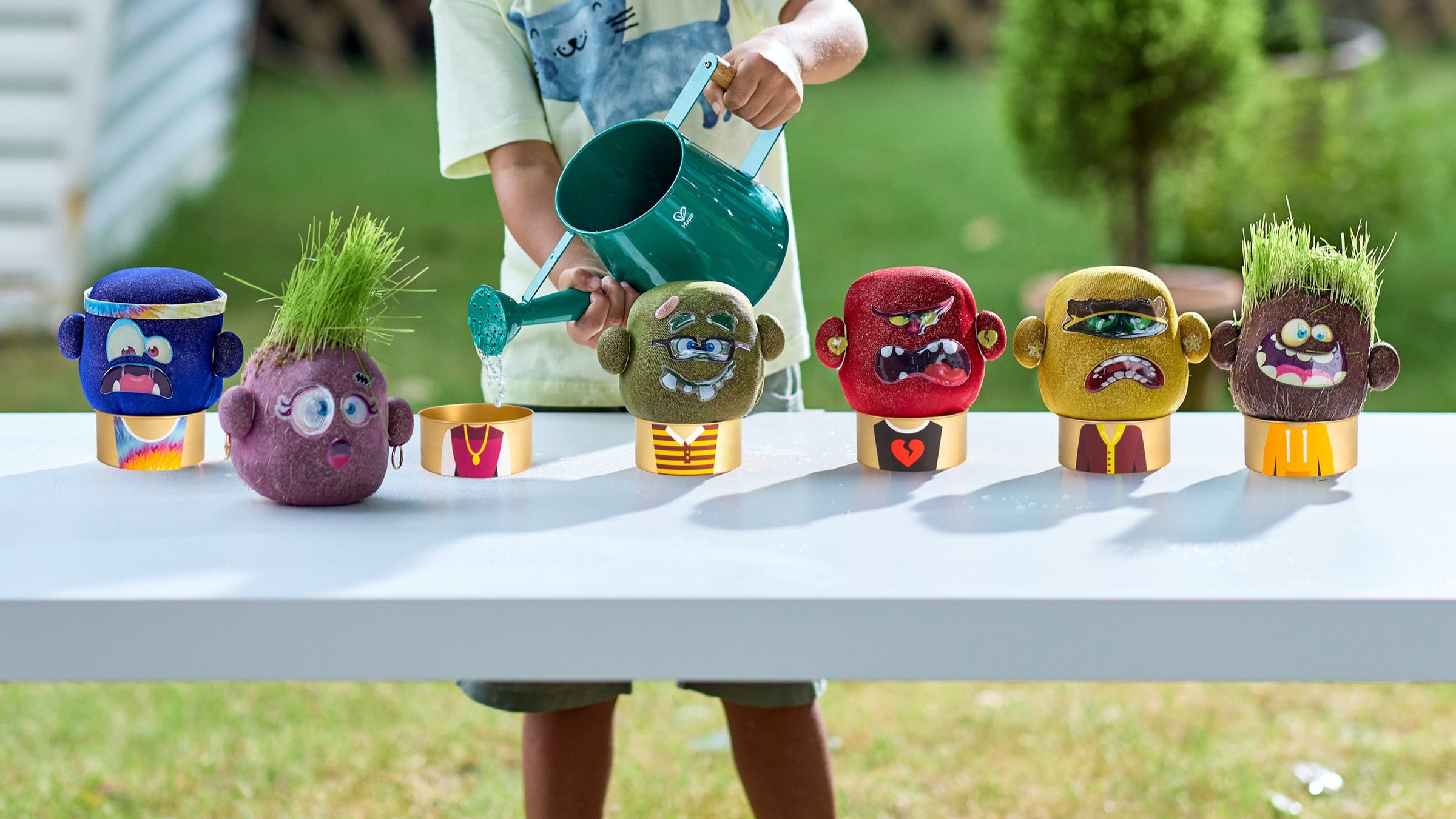 Colorful toy planters with faces on a table outdoors, plant pals plant growing toys