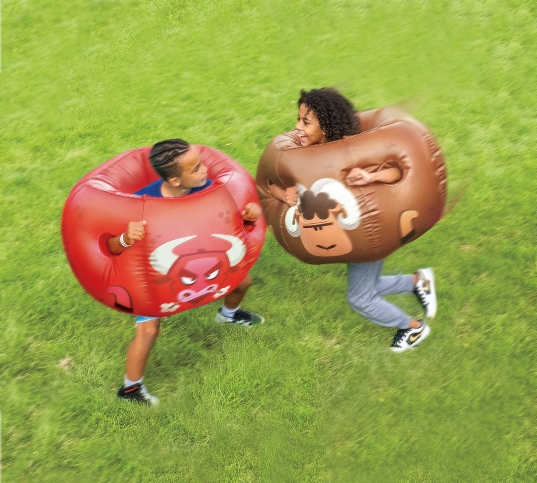 Two people wearing Rovers blow-up bumper balls featuring cartoon bull and sheep designs playing on green grass outdoors